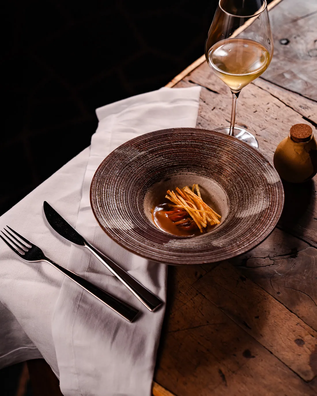Moule, frite, tajine servi dans un bol de céramique, table en bois